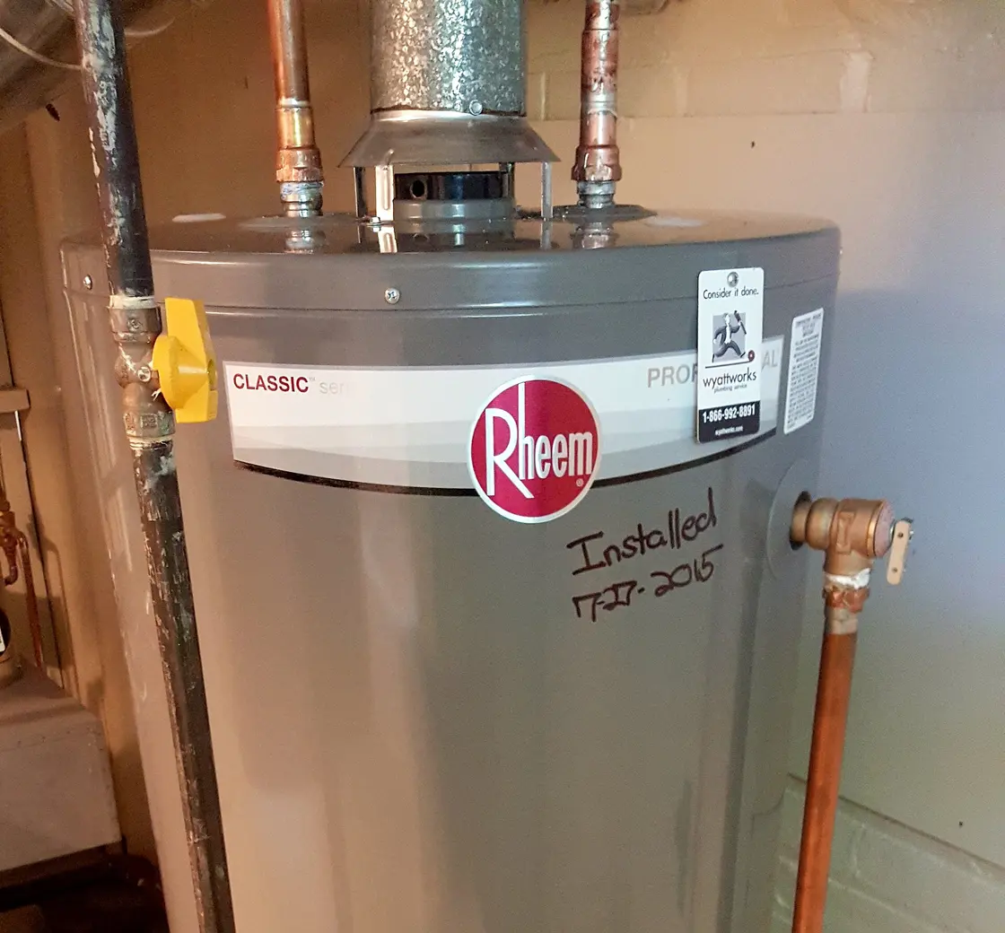 Gas water heater installed against a brick basement wall