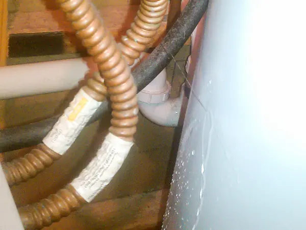 Close-up of the water and gas connections on top of a water heater