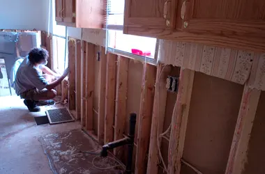 Kitchen with water-damaged walls opened up around the plumbing