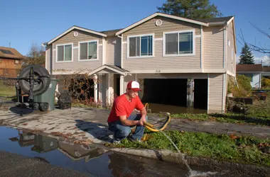 Man pumping water out of a flooded house through a hose