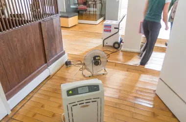 Fan and dehumidifier being carried into a water-damaged home