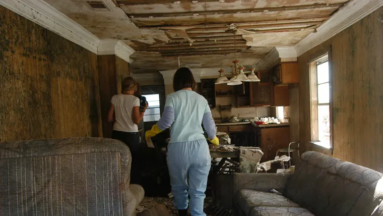 Crew in protective suits clearing a room with a collapsed, water-damaged ceiling