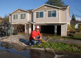 Man pumping flood water out of a house through a hose