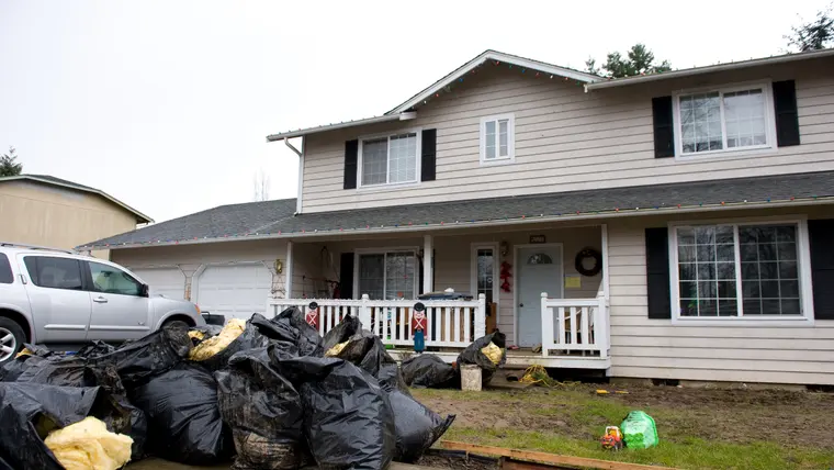 Flood-damaged belongings bagged outside a house