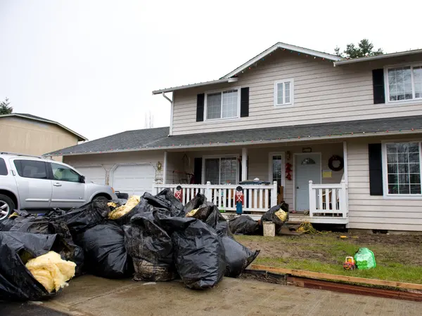 Bags of flood-damaged belongings piled outside a house